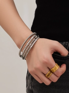 Detail von mehrlagigen Silberperlen-Armbändern mit Zirkonia und goldenen Ringen am Modell