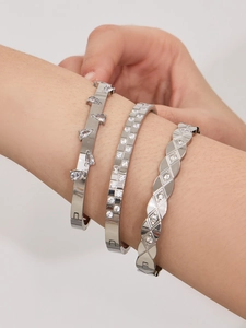 Detailed view of three layered stainless steel bracelets with teardrop and pavé zircons