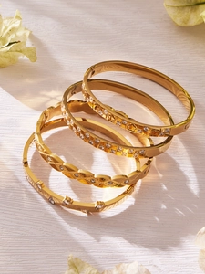 Detail of four luxury 18k gold plated stainless steel bangles with zircon inlay patterns