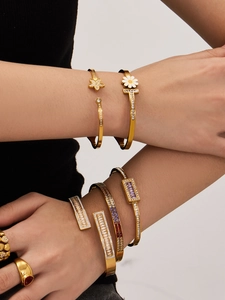 Detalle macro de pulseras de margaritas doradas con piedras de circón en las muñecas