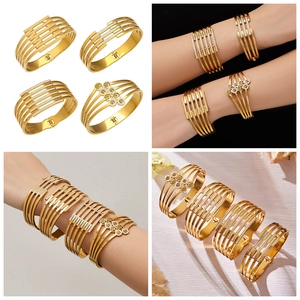 Details von vier goldenen Mehrschicht-Armreifen mit Lebensbaum und Zirkon-Anhängern
