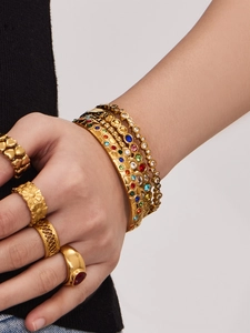 Detail von 18k vergoldeten Edelstahl-Armbändern und Ringen mit bunten Zirkonia-Inlays
