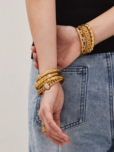 Detailed layered shot of 18k gold-plated cuff bracelets and chains with cubic zirconia