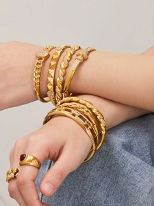 Détails de joncs en acier doré 18 carats et bagues en zircon portés par un mannequin femme