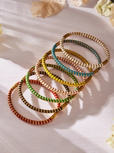 Detailaufnahme von sieben bunten Emaille-Armreifen mit goldener strukturierter Oberfläche