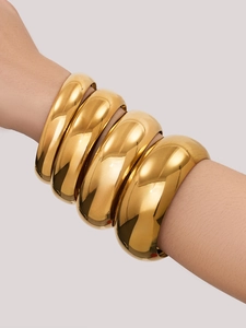 Detalle de brazaletes apilables bañados en oro de 18k con acabado de espejo pulido brillante