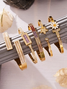 Detalle macro de pulseras doradas adornadas con circonitas y gemas de colores
