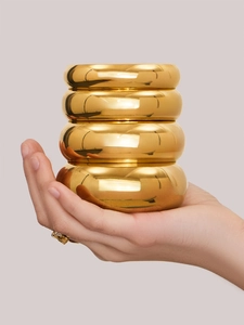 Detalle de cuatro brazaletes apilados chapados en oro de 18k con acabado pulido espejo