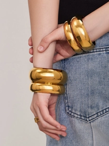 Primer plano de un brazalete de acero inoxidable pulido chapado en oro de 18 quilates