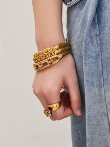 Macro shot of 18k gold plated bracelet stack and heart ring with red gemstone