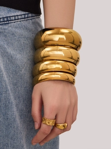 Detalle de brazaletes y anillos de acero inoxidable chapados en oro 18k en el brazo de modelo