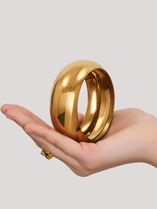 Primer plano de un brazalete de acero inoxidable chapado en oro 18k pulido espejo