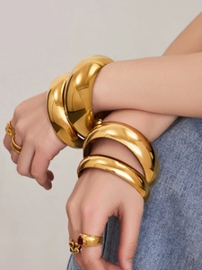 Primer plano de brazaletes y anillos apilables de acero inoxidable chapado en oro de 18k