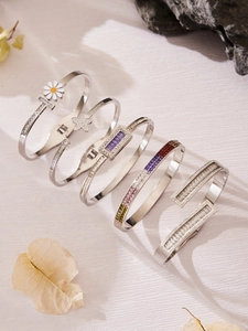 Detalle de cinco brazaletes plateados con diseños de margaritas y circonitas de colores