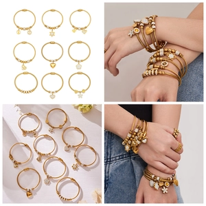 Set di 9 bracciali dorati con ciondoli a cuore e stella indossati a strati da una modella