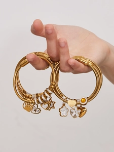 Dettaglio di bracciali a filo placcati oro 18k con ciondoli zircone cuore e stella