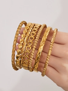 Detail of 18k gold plated geometric bangles featuring heart patterns and braided textures