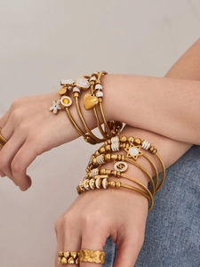 Dettaglio di bracciali e anelli placcati oro 18k sovrapposti con zirconi