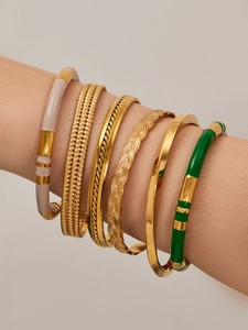 Detail of 6-piece gold stacked bracelet set with green enamel and braided textures