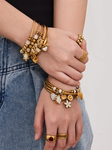 Dettaglio di bracciali in acciaio inossidabile placcati oro 18k con ciondoli zirconi