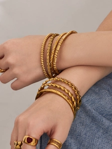 Dettaglio del set di bracciali e anelli geometrici placcati in oro 18 carati
