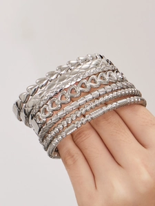 Vista macro di bracciali argentati a strati con maglie a cuore e texture a torciglione