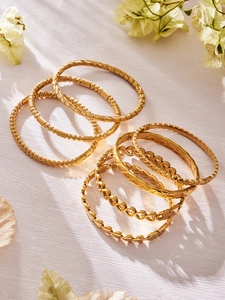 Dettaglio di bracciali geometrici placcati oro 18k con motivi a cuore e diamantati