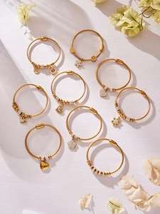 Dettaglio di bracciali a cavo in acciaio placcati oro 18k con ciondoli in zircone lucido