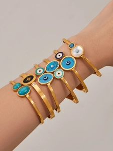Détail de joncs bohèmes dorés avec turquoise, nacre et œil protecteur au poignet