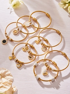 Detailansicht goldener Edelstahlarmbänder mit Zirkon-Herzanhängern und Auge des Bösen