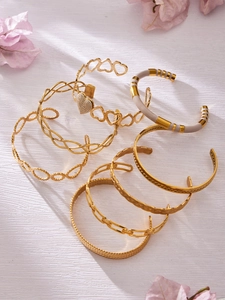 Detail of gold-plated bangle set with hollow hearts and enamel drip design