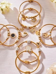 Makro-Detail von goldenen Kabelarmbändern mit Herz- und Böser-Blick-Anhängern