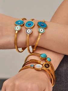 Détail de bracelets mauvais œil dorés superposés avec accents turquoise et émail