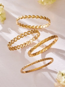 Detail showing 18k gold plated geometric bangles with heart motifs and diamond accents