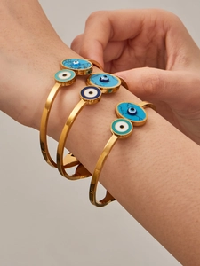 Gros plan de bracelets œil protecteur dorés avec détails en turquoise et émail bleu