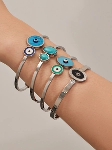 Détail de cinq bracelets œil porte-bonheur argentés avec touches de turquoise et émail