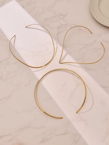 Dettaglio di tre girocolli minimalisti placcati in oro 18k su sfondo di marmo di alta qualità