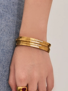 Detail showing stacked gold bangles with zircon inlay and a heart-shaped ruby ring