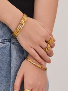 Detail of 18k gold plated stainless steel bangles and rings set with pavé zircon