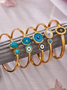 Détail de bracelets dorés avec turquoise et œil bleu sur un support de colonne