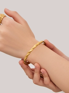 Detalle de un brazalete de cuerda trenzada chapado en oro de 18k y un anillo de flores