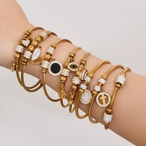 Goldenes Edelstahl-Armreif-Set mit Zirkonia und Herzanhänger am Handgelenk des Models
