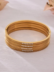 Close-up of four stackable 18k gold plated stainless steel bangles with zircon inlay