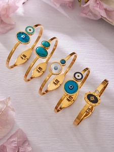 Lot de cinq bracelets dorés avec turquoise et breloques œil bleu sur fond blanc