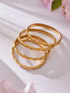 Primer plano de set de brazaletes de acero inoxidable chapados en oro de 18k