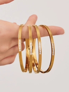 Close-up of four gold-plated textured bangles with micro-pave cubic zirconia stones