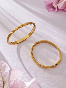 Detalle de los brazaletes de acero inoxidable chapados en oro de 18k con diseño de cuerda tejida