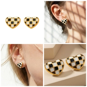 Détail macro de boucles d'oreilles cœur à damier avec finition dorée et émail chic