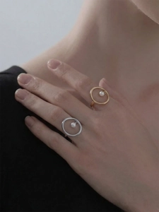 Detailansicht minimalistischer Perlenringe in Gold und Silber an der Hand des Models
