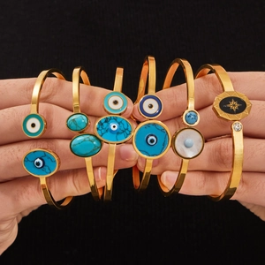 Set de bracelets bohèmes dorés avec breloques œil bleu turquoise sur fond noir texturé
